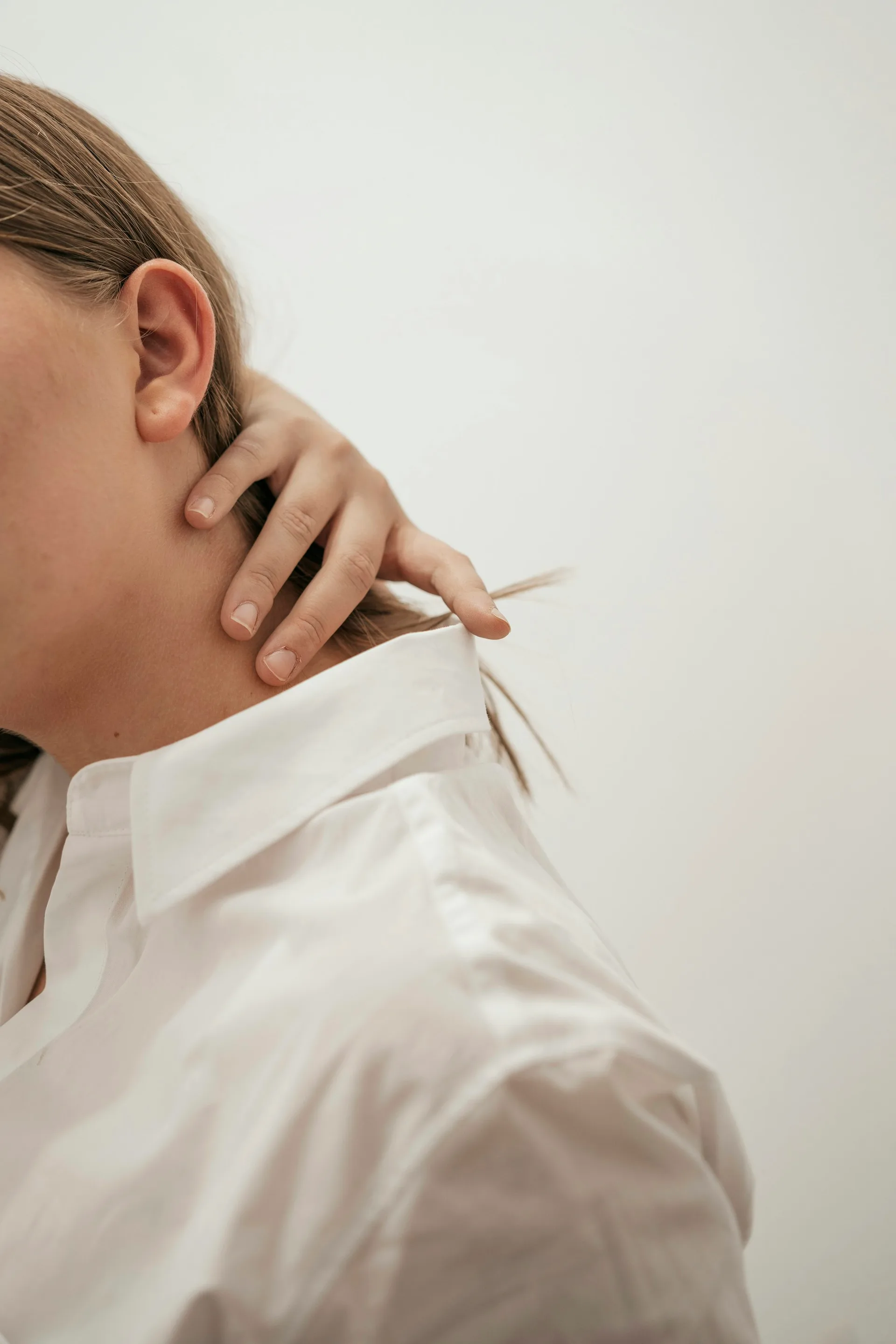 A person rubbing the back of their neck after an injury.