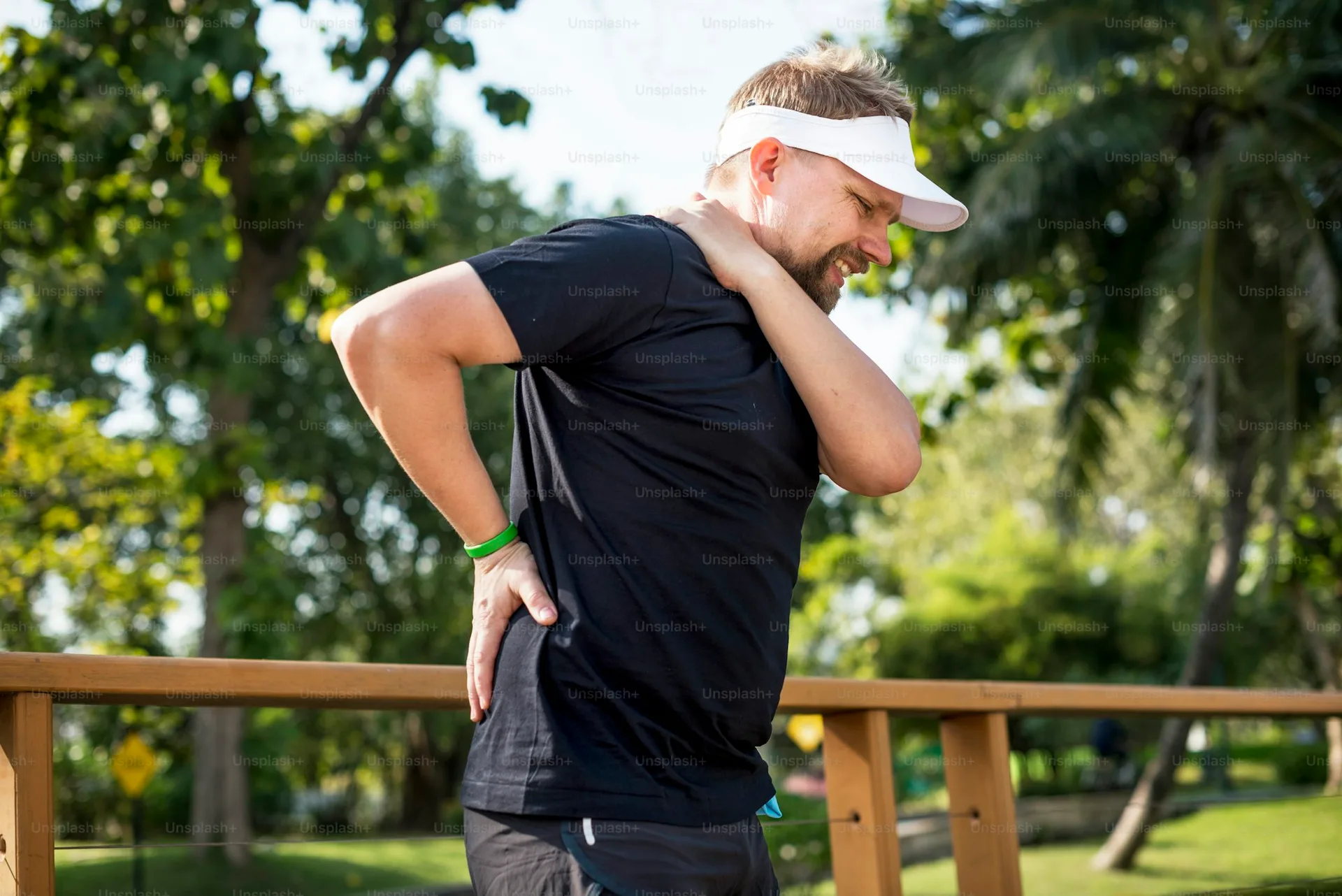 A runner stretching outdoors to ease back tension.