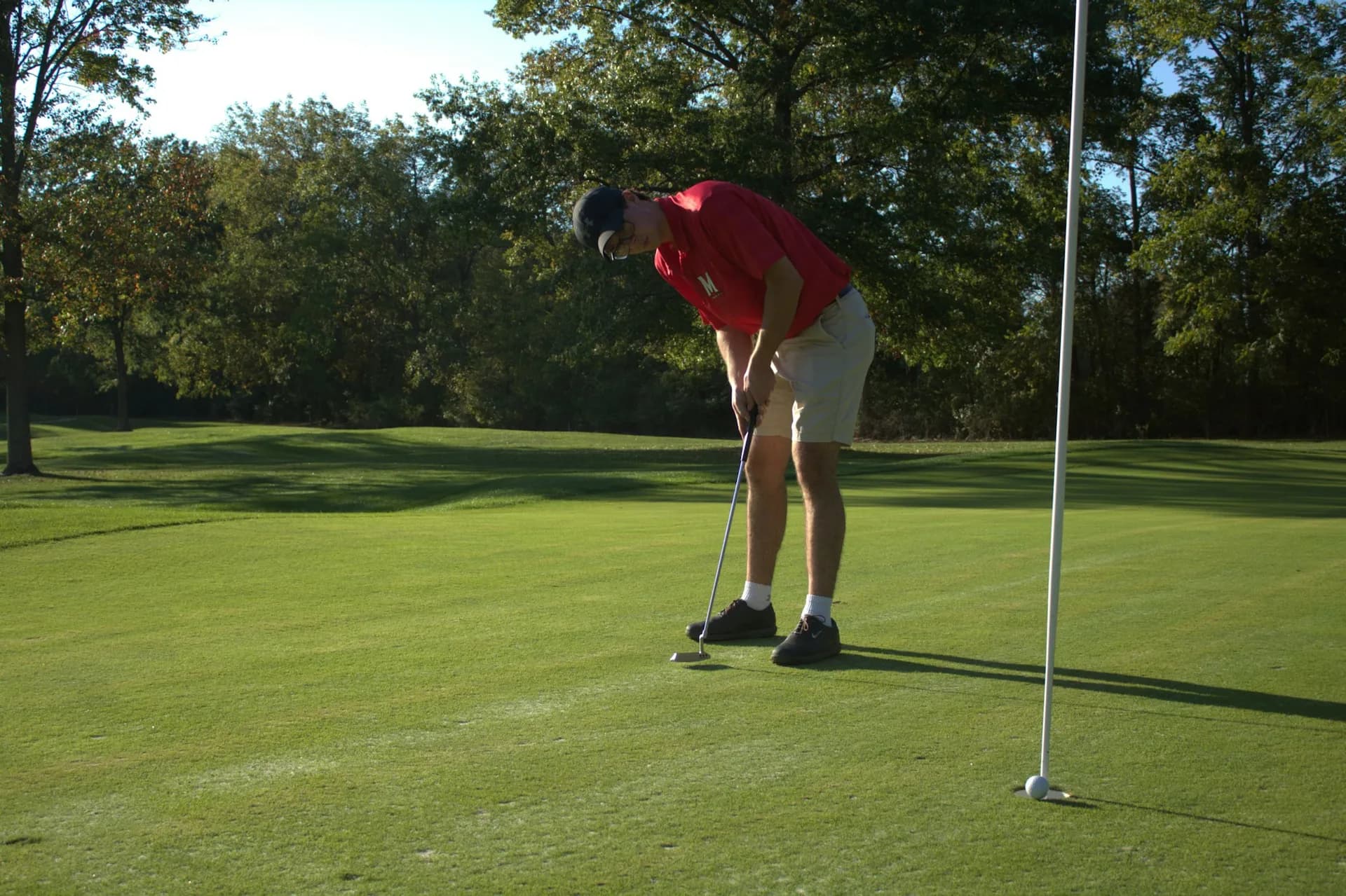 An adult golfer mid-swing on a fairway.